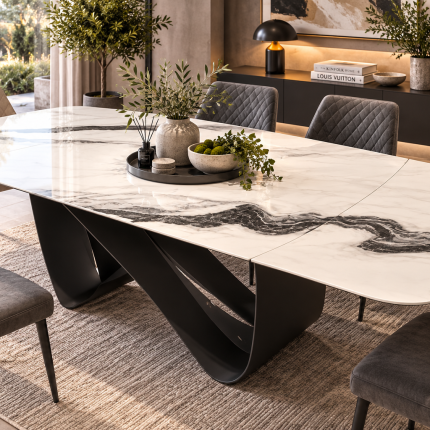 White marble effect extending ceramic dining table with dramatic black veining, rounded corners and black sculptural pedestal base