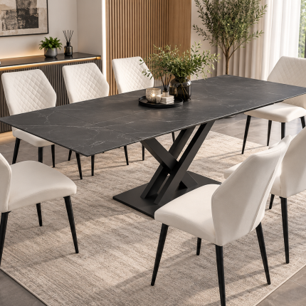 Charcoal grey extending dining table with black X-frame pedestal base and eight cream upholstered dining chairs