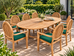 8 seater teak oval extending garden dining table with eight high-back armchairs and green cushions on a patio